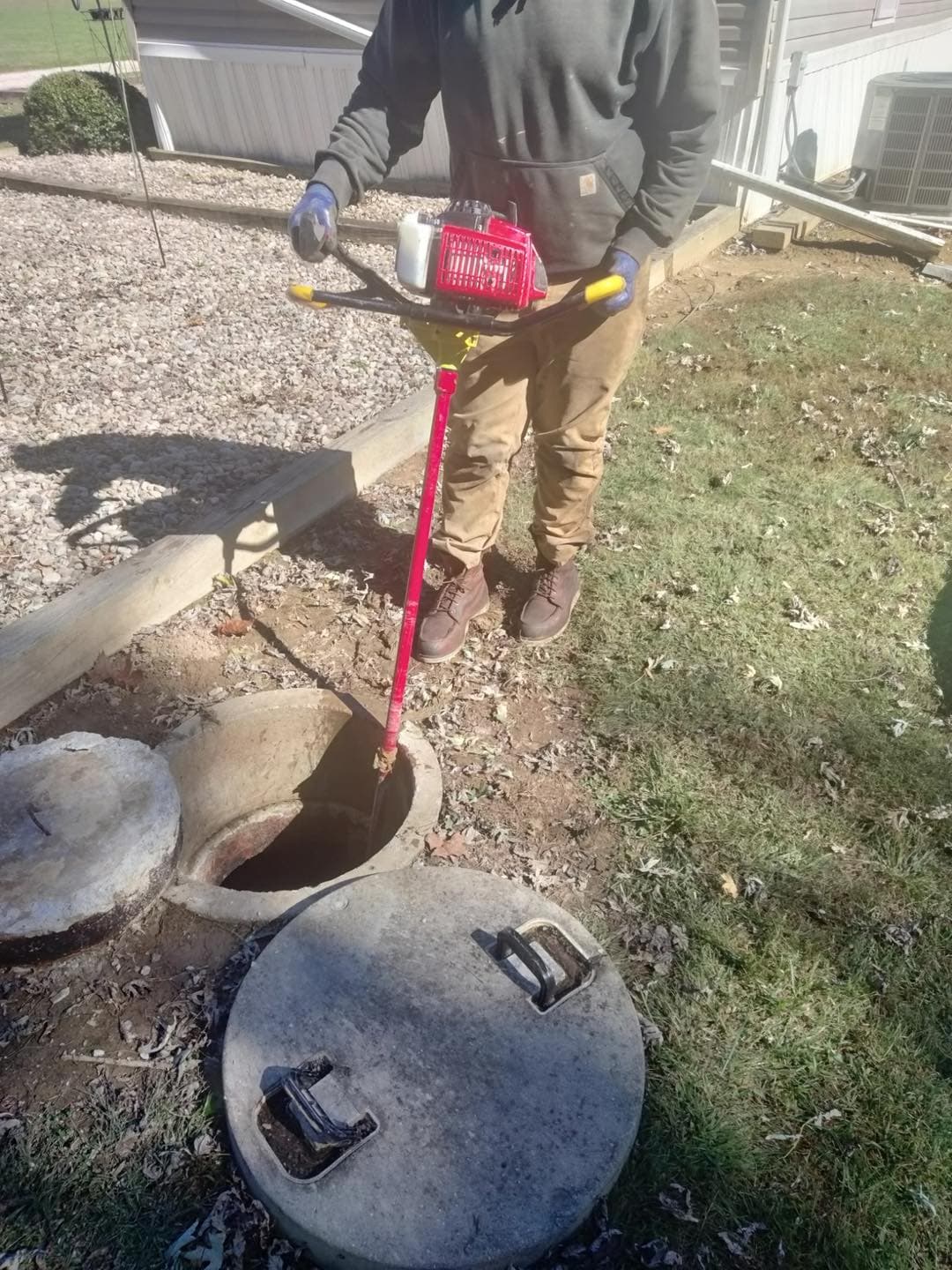 Worker using crud buster equipment on an open septic tank
